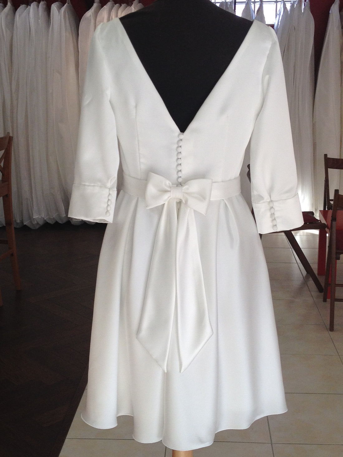 Robe courte à nœud dans le dos, sur mannequin à l’atelier