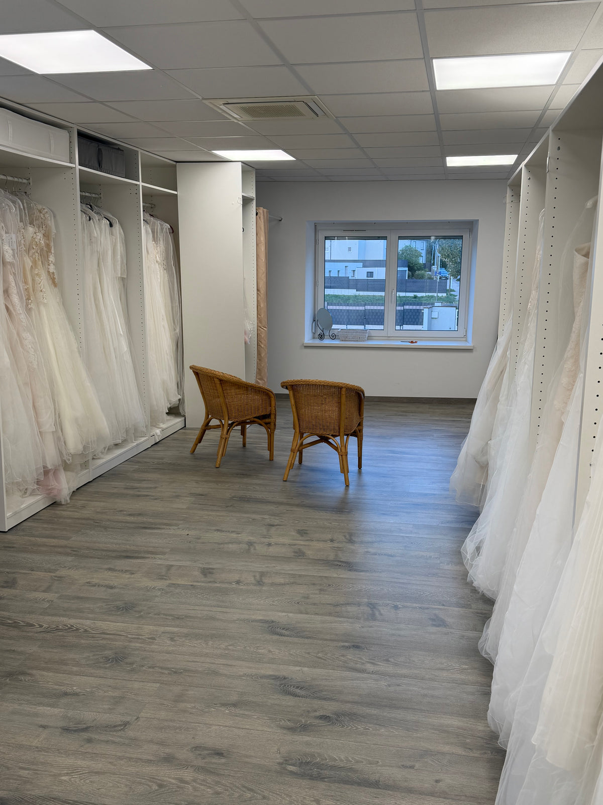 Le showroom Tiffany Mariée à Niedermodern : les robes sur leurs portants et deux fauteuils d'essayage